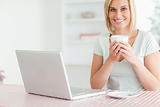 Close up of a woman holding coffee with laptop in front of her l