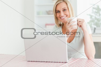 Close up of a woman holding coffee with laptop