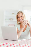 Close up of a woman holding cup of coffee with laptop 