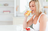 Woman sitting at a table drinking orange juice