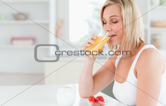 Woman sitting at a table drinking orange juice