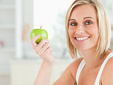 Young woman holding a green apple looking into camera