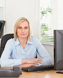 Serious blonde woman sitting behind a desk