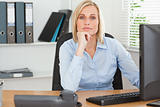 Serious woman with chin on hand behind a desk