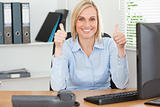 Young woman sitting behind desk with thumbs up 