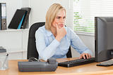Working thoughtful woman in front of a screen looking at it 
