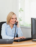 Smiling blonde businesswoman on the phone looking at her screen