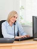 Smiling businesswoman on the phone while typing looks at screen