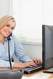 Charming blonde businesswoman on the phone while typing 
