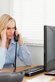 Businesswoman on phone looking at screen while having headache
