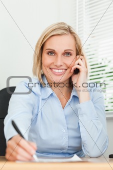 Portrait of a businesswoman looking into camera while noting som