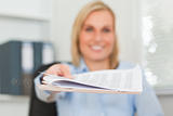 Smiling businesswoman passing a paper looks into camera