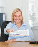 Smiling blonde businesswoman passing a paper looking at it
