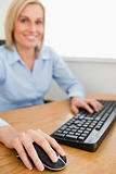 Blonde smiling businesswoman with hands on mouse and keyboard