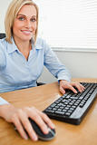 Smiling businesswoman with hands on mouse and keyboard