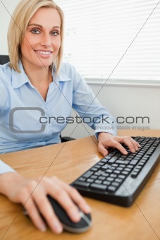 Smiling businesswoman with hands on mouse and keyboard