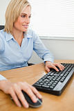 Smiling businesswoman with hands on mouse and keyboard looking a