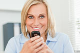 Smiling woman with mobile looking into camera