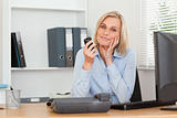 Smiling blondebusinesswoman with mobile looking into camera