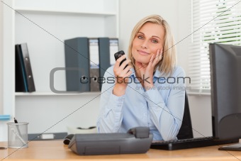 Smiling blondebusinesswoman with mobile looking into camera