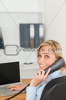 Blonde businesswoman smiling into camera while on the phone