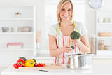 Woman cooking broccoli looks into the camera