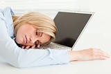 Cute blonde woman sleeping on her notebook holding cup 
