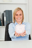 Gorgeous blonde businesswoman holding a piggy bank 