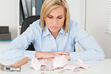 Sulking woman sitting in front of an shattered piggy bank 