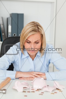 Sulking woman sitting in front of an shattered piggy bank