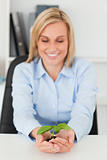 Smiling businesswoman looking at little green plant