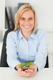 Smiling businesswoman holding a little green plant looking into 