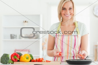 Close up of a young woman frying peppers looking into the camera