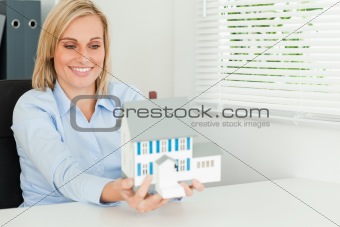 Gorgeous businesswoman presenting model house looking at it