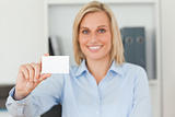 Blonde businesswoman holding a card looks itno camera
