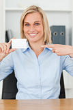 Smiling blonde businesswoman pointing at a card