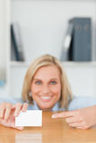 Businesswoman pointing at a card crouching behind her desk