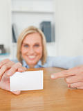 Blonde smiling businesswoman pointing at a card crouching 