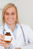 Smiling doctor holding medicine to camera