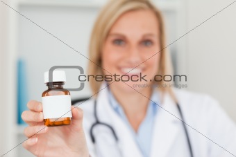 Gorgeous doctor holding medicine to camera