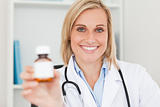 Gorgeous blonde doctor holding medicine to camera