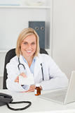 Smiling doctor holding prescription looks into camera