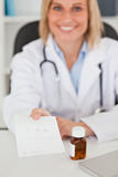 Smiling doctor giving prescription looks into camera