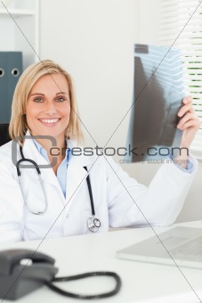 Charming doctor holding x-ray smiles into camera