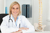 Smiling doctor with model spine next to her 