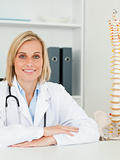 Smiling doctor with model spine next to her looks into camera