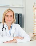 Serious doctor with model spine next to her looks into camera