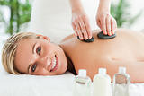 Blonde smiling woman experiencing a stone therapy
