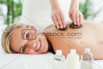 Blonde smiling woman experiencing a stone therapy