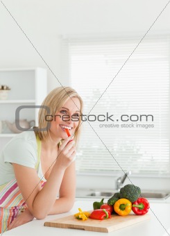 Portrait of a young woman eating red peppers